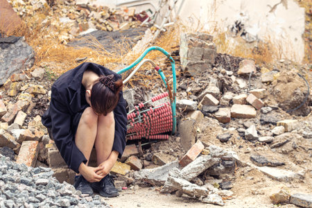 A girl next to a house destroyed by the war. War in Ukraine.の写真素材