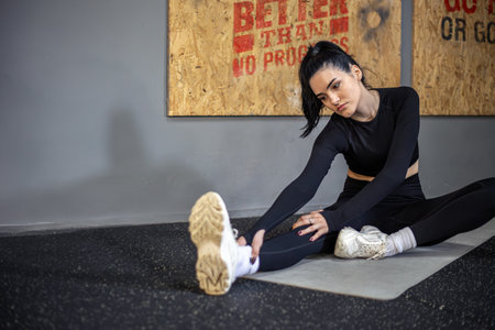 Women warm up and stretching legs in gym. Young beautiful girl in the gym.の写真素材