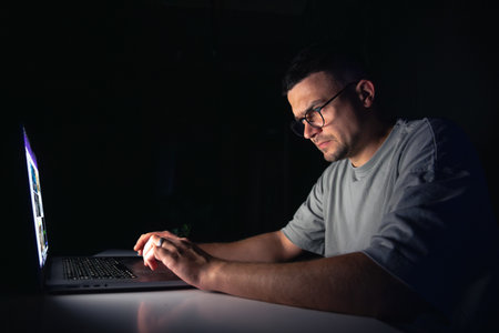Young man works at the computer at night.の写真素材