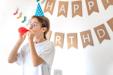 A festive girl inflates a balloon on her birthday. Birthday concept.の写真素材