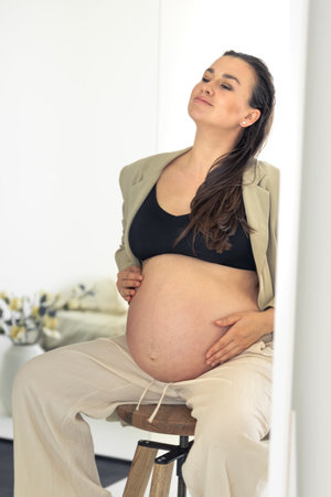 Stylish pregnant woman sitting on a chair. Pregnancy and style concept.の写真素材