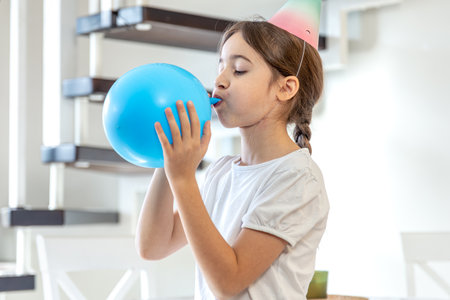 The girl inflates a balloon. Birthday concept. A girl with an inflatable ball.の写真素材