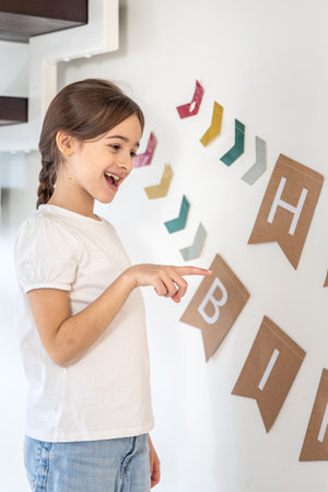 Preparation for the birthday. Girl hangs Happy Birthday sign on a wall.の写真素材