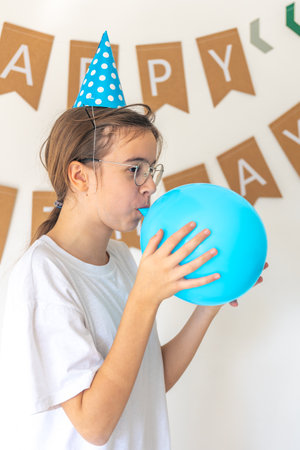 A festive girl inflates a balloon on her birthday.の写真素材