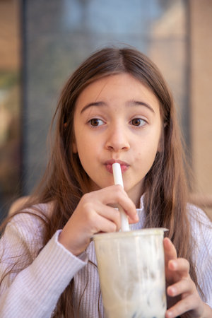 A happy girl drinks a prepared drink in a cafe. A girl with a drink.の写真素材