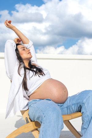 Joyful pregnant woman on the background of the sky. Concept of pregnancy.の写真素材