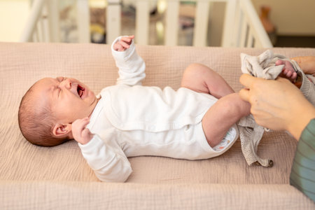 Mother wearing clothes to her baby. Baby healthcare hygiene concept.の写真素材