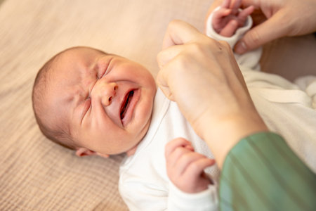 Mother wearing clothes to her baby. Baby healthcare hygiene concept.の写真素材