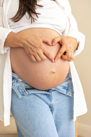 A heart from the hands on the belly of a pregnant woman. Concept of pregnancy.の写真素材