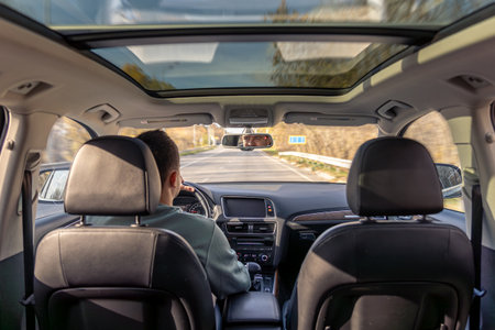 Driving the modern car on asphalt road. A young man drives a car.の写真素材