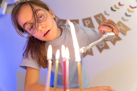 Birthday concept. The girl lights the candles on the festive cake.の写真素材
