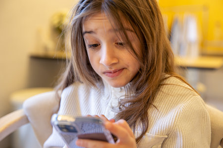 Happy relaxed young girl sitting on couch using cell phone. A girl with a phone.の写真素材