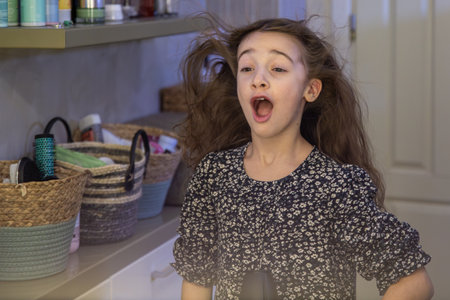 A girl dries her hair with a hairdryer in the bathroom. Hygiene concept.の写真素材