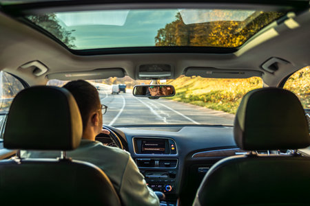 Driving the modern car on asphalt road. A young man drives a car.の写真素材