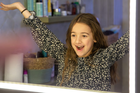 The girl looks in the mirror. The girl in the bathroom.の写真素材