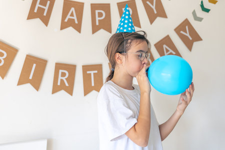 A festive girl inflates a balloon on her birthday. Birthday concept.の写真素材