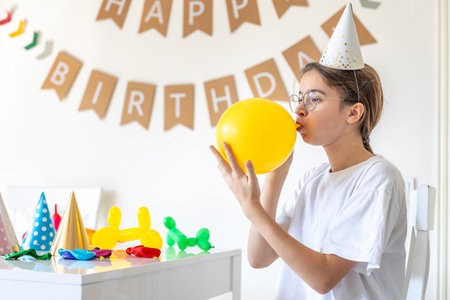 A festive girl inflates a balloon on her birthday. Birthday concept.の写真素材