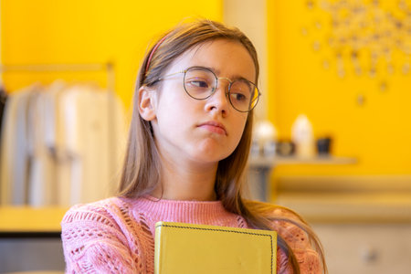 Sad teenage girl with a book in her hands. Emotion concept.の写真素材