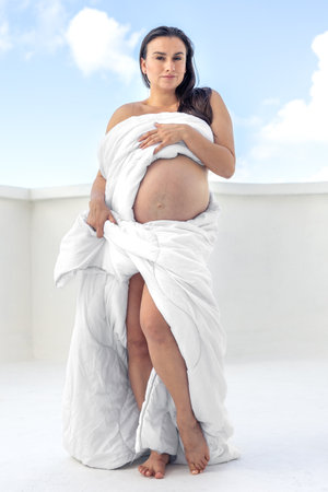 Beautiful pregnant woman covered with a white blanket. Concept of pregnancy.の写真素材