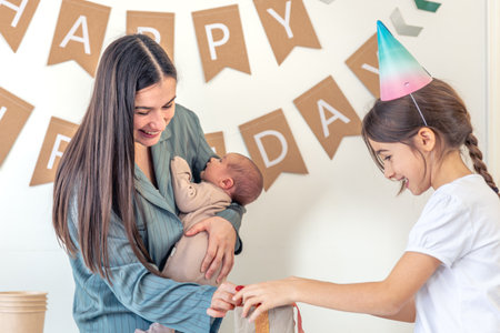 Mother and daughter unwrap a gift. Birthday party at home.の写真素材