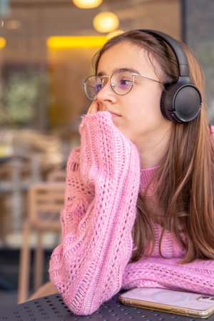 Sad teenage girl listens to music in headphones. Emotions concept.の写真素材