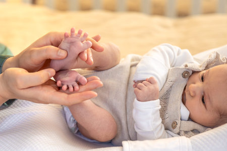 Parent holding in the hands feet of newborn baby. Mom holding baby feet.