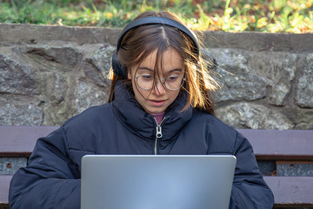 A girl in headphones works at a laptop. A girl with a laptop.の写真素材
