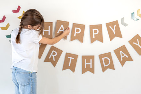 Preparation for the birthday. Girl hangs Happy Birthday sign on a wall.の写真素材