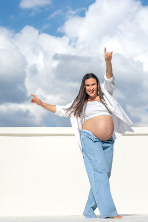 Joyful pregnant woman on the background of the sky. Concept of pregnancy.の写真素材
