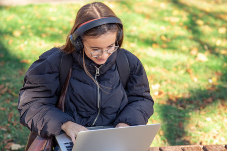 Happy teenage girl in headphones works on a laptop. Emotions concept.の写真素材