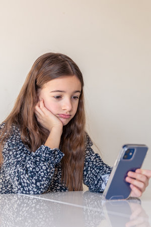 Sad girl with a phone. Sad girl with hand on chin using mobile phone.の写真素材