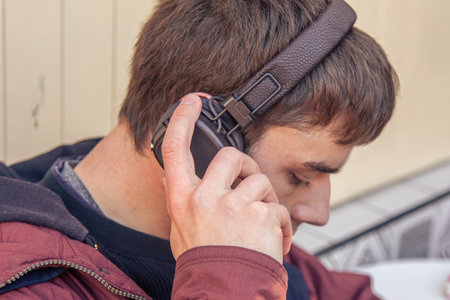 A man listens to music in headphones. A mans hand holds an earphone.の写真素材