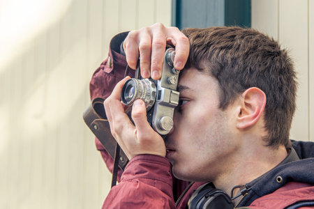 A young man takes pictures on a vintage camera. Film camera photography.の写真素材
