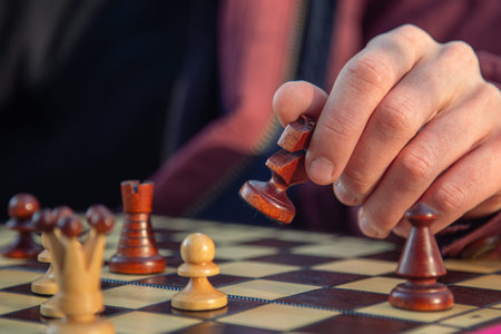 A chess piece in a mans hand on a chessboard. A game of chess.