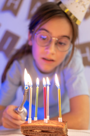 Birthday concept. The girl lights the candles on the festive cake.の写真素材