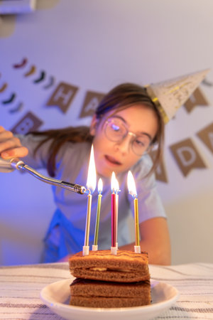 Birthday concept. The girl lights the candles on the festive cake.の写真素材