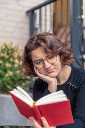 A stressed young woman is reading a book. Emotions concept.の写真素材