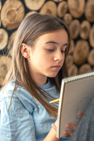 Girl draws in a notebook. The girl draws. School homework.