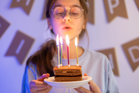 A happy girl is holding a festive cake with candles in her hands. Birthday.の写真素材