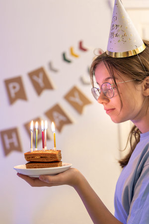 Birthday concept. The girl blows candles on the cake.