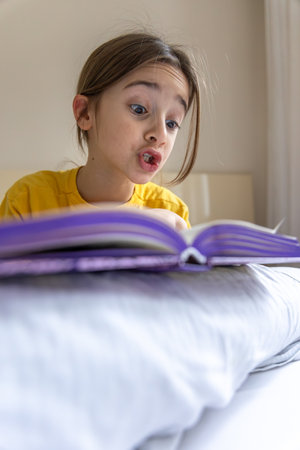 An interested and happy girl is reading a book. Emotion concept.の写真素材