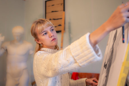 Young female artist painting on easel in studio. Art concept. A woman draws.の写真素材