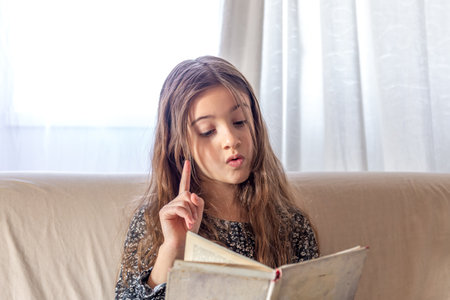 An interested girl is reading a book at home. A girl and a book.の写真素材