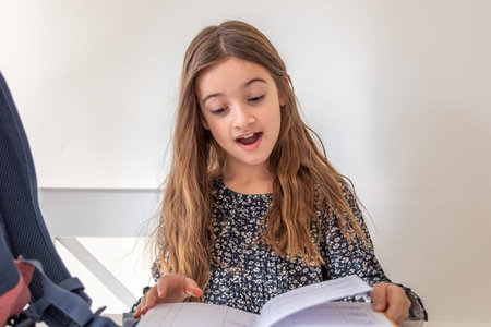 Happy girl reading a book at home. The girl is preparing for lessons at school