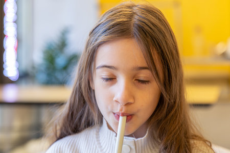 A happy girl drinks a prepared drink in a cafe. A girl with a drink.の写真素材