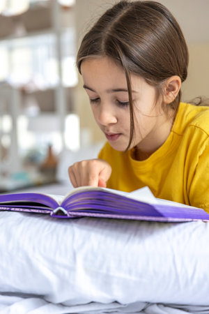 An interested and happy girl is reading a book. Emotion concept.の写真素材