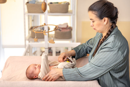 Mother wearing clothes to her baby. Baby healthcare hygiene concept.の写真素材