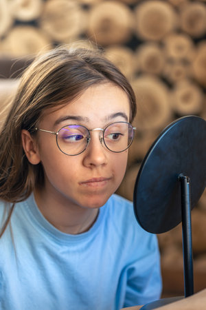 A beautiful girl in glasses looks at herself in the mirror.Morning routine.の写真素材