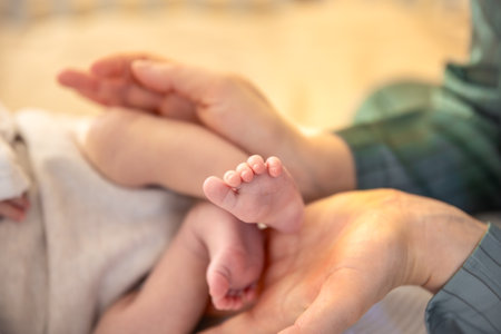 Parent holding in the hands feet of newborn baby. Mom holding baby feet.の写真素材