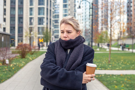 Sad young woman in the city. The woman is cold outside. A walk in the city.の写真素材